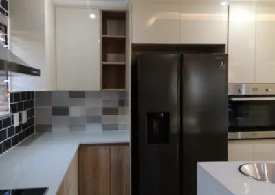 Cream kitchen cabinetry beside a built-in fridge