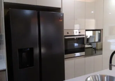 Built-in fridge beside cream high-gloss cabinetry