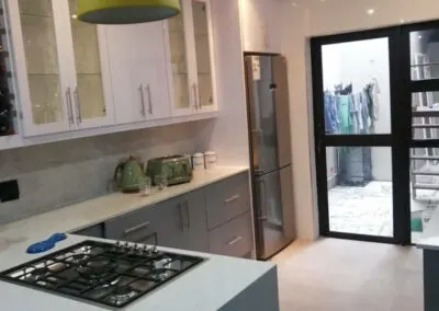White kitchen with a gas hob and a glass door to the yard