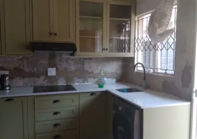 Sage green fitted kitchen with a black countertop