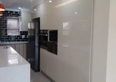 Cream gloss kitchen cabinetry along a hallway